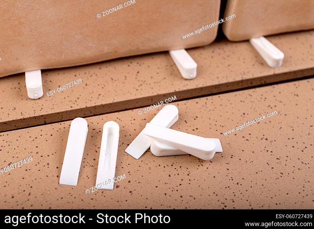 White plastic clinics for laying ceramic tiles. Accessories and tools necessary for construction workers. Light background