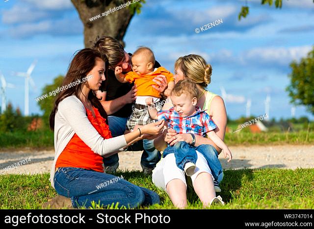 Family - Grandmother, mother, father and children sitting and playing in garden
