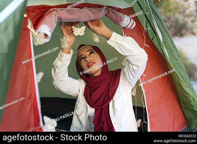 Young tourist woman wearing Hijab decorating a tent