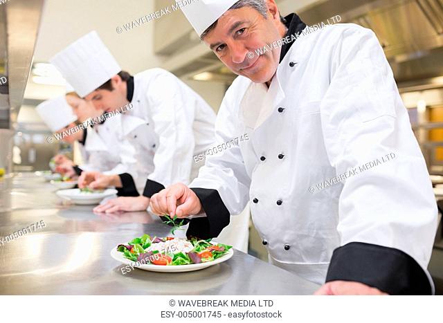 Smiling Chefs preparing their salads in the kitchen