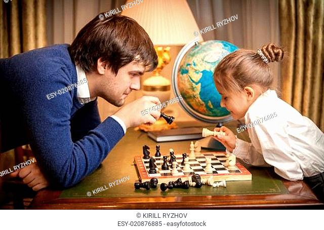 Handsome man playing chess with girl