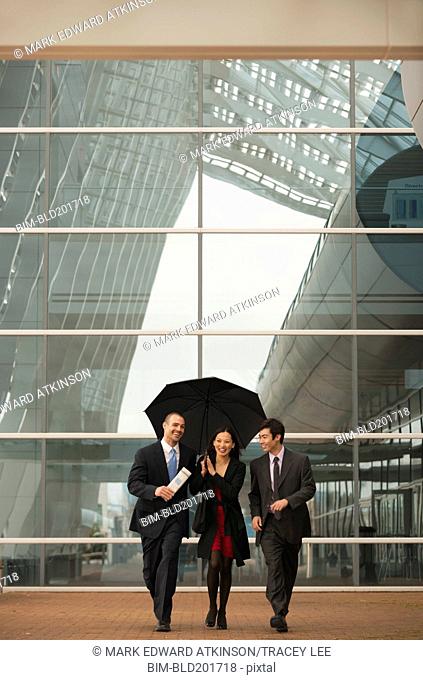 Business people walking together with umbrella