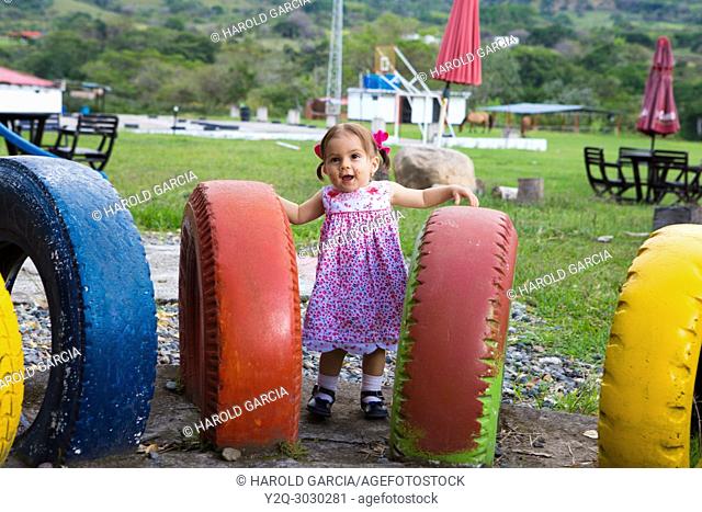Baby girl playing in a play ground full of colorful tires