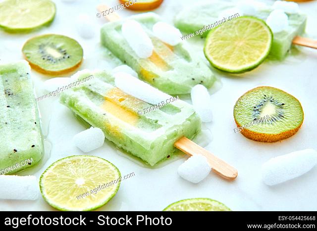 Frozen fruit juice lolly with a piece of peach and pieces of fruit and ice on a gray background. Healthy summer dessert