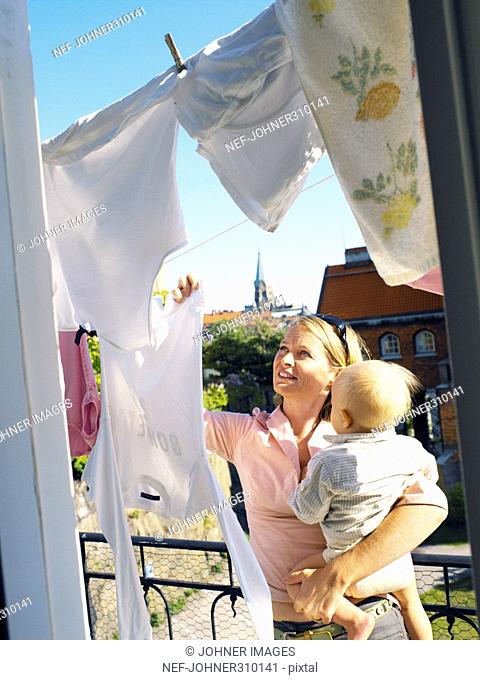 A mother with her child hanging laundray