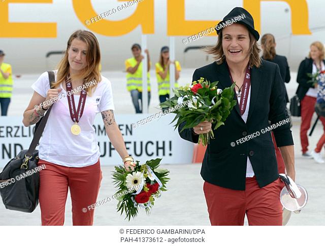 Goal keeper of the German women's national soccer team, Nadine Angerer (R), and player hold the trophy and a bouquet of flowers after the arrival at the airport...