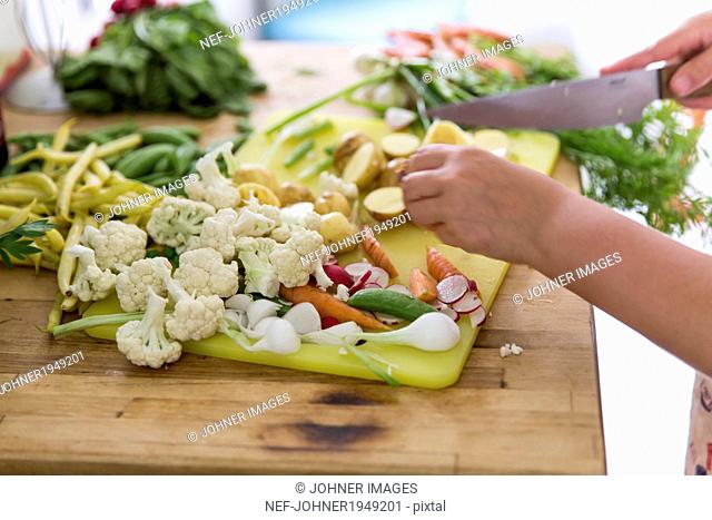 Girl cutting vegetables in kitchen, Sweden
