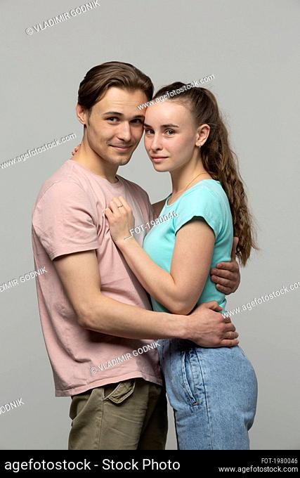 Studio portrait happy young couple hugging
