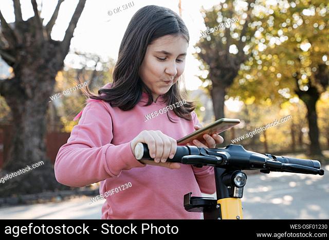 Girl using smart phone to rent electric scooter