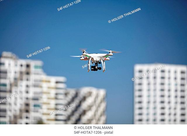 Drohne fliegt in blauem Himmel in der Nähe von Hochhäusern