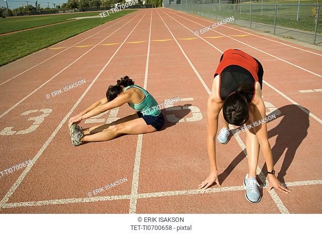 Female runners stretching on track, Utah, United States