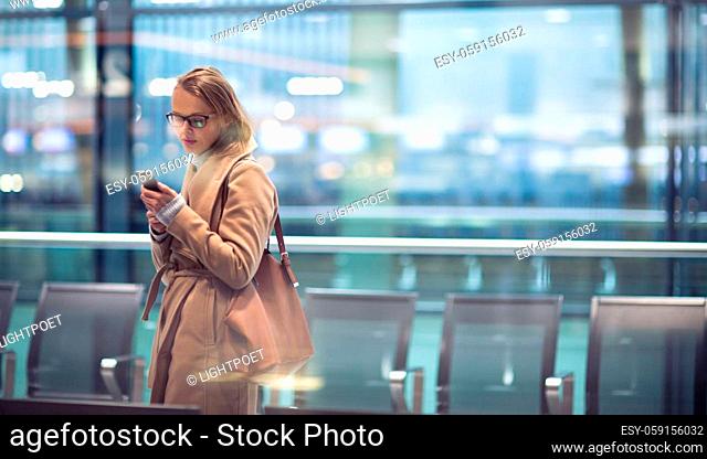 Young female passenger at the airport, using her tablet computer while waiting for her flight (color toned image)