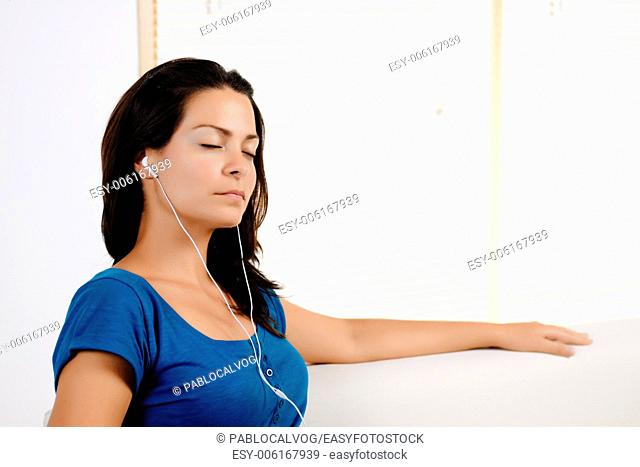 Portrait of a beautiful young woman relaxing while listening to music at home