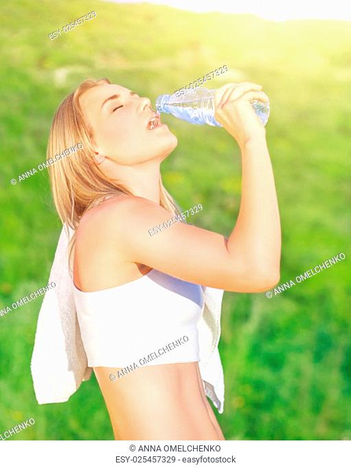 Happy tired woman drink water after workout in the park, enjoying training outdoors in sunny day, sportive and healthy lifestyle