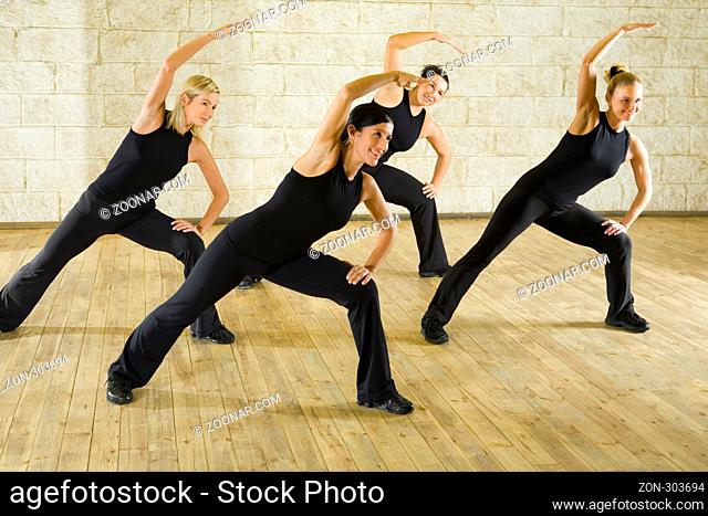 A group of women exercising in the fitness club. They're smiling. Front view