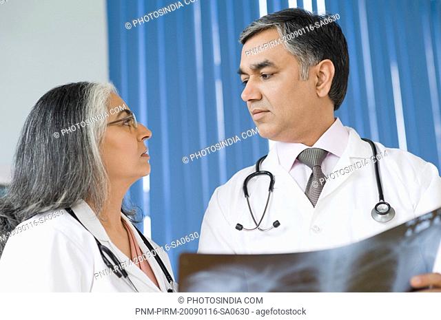 Female doctor discussing with a doctor holding an x-ray report, Gurgaon, Haryana, India