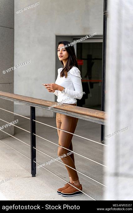 Young woman holding smartphone on balcony