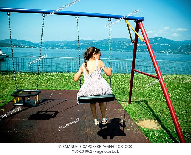 Little girl on the swing on the banks of Lake Maggiore, Ispra, Lombardy, Italy