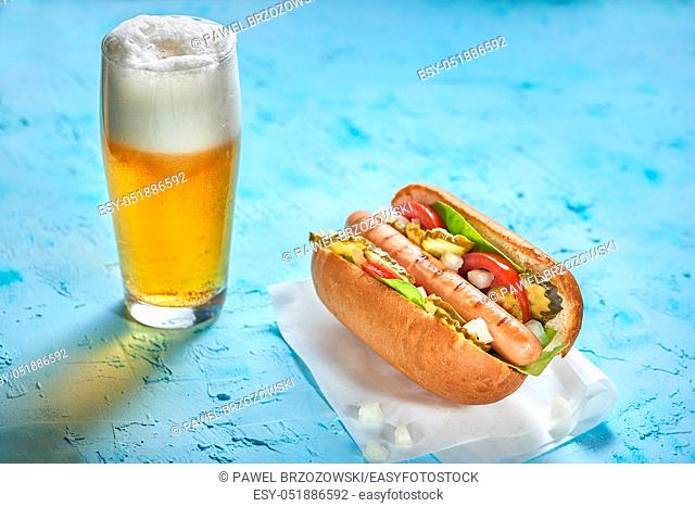 Hot dog with beer on the blue background. Fatty, eating