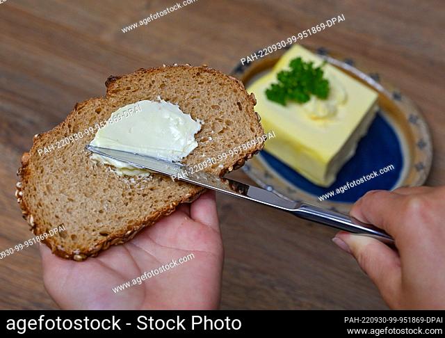 29 September 2022, Brandenburg, Sieversdorf: A girl spreads butter on a slice of bread. There will be a particularly delicious breakfast on September 30, 2022