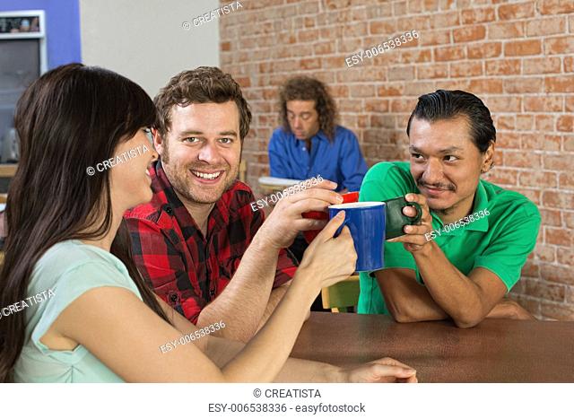 Diverse trio of friends toasting with coffee mugs
