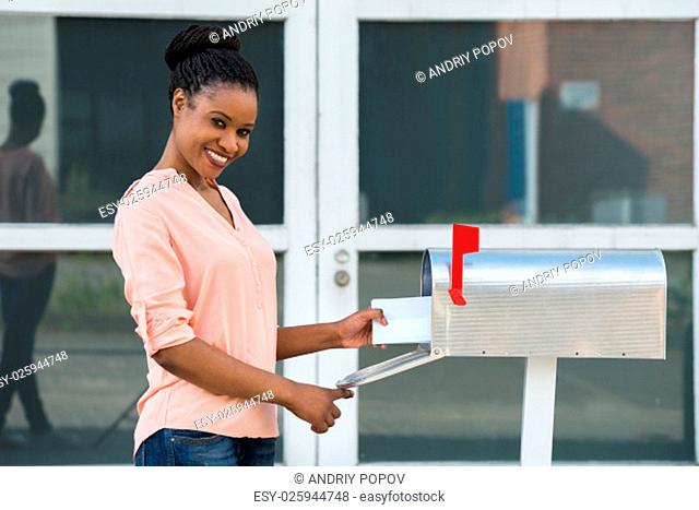 Smiling Young African Woman Collecting Her Mail From Mailbox