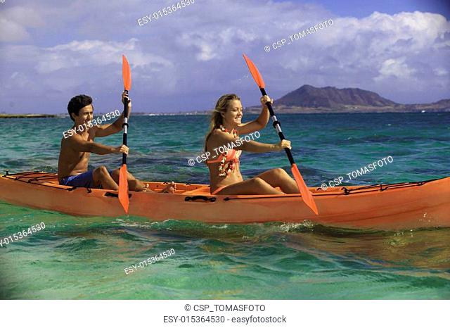 couple paddling their kayak in hawaii