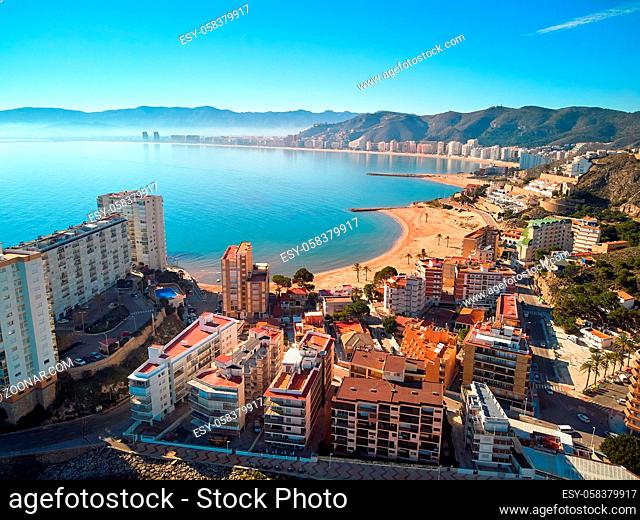 Aerial drone point of view Cullera sandy empty beach and townscape rooftops during sunny winter day. Touristic famous place