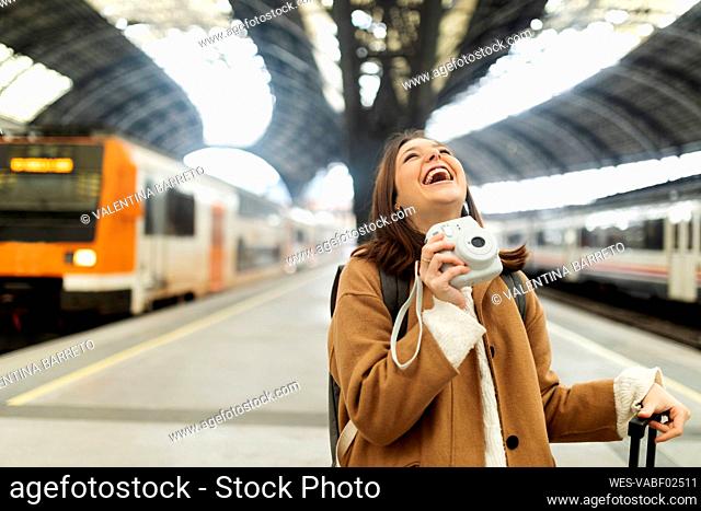 Happy young woman with camera at the train station