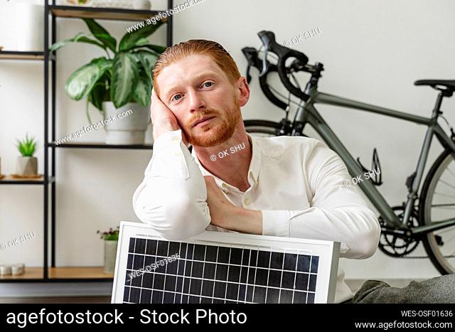Businessman leaning on solar panel in office