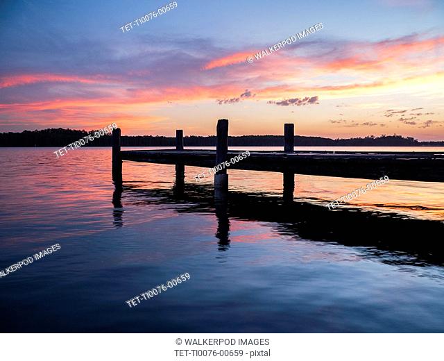 Jetty on river at sunset