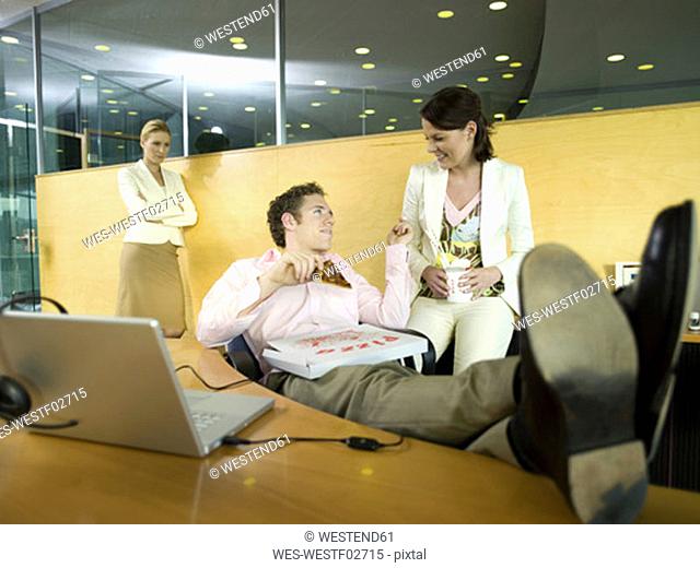 Couple having lunch in office, woman watching