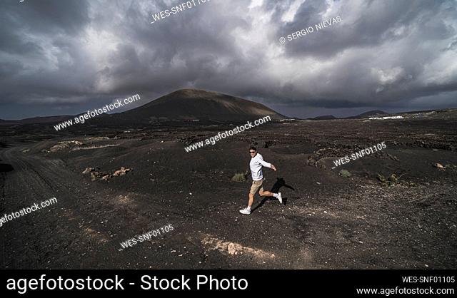 Happy male tourist dancing on volcano ash at El Cuervo Volcano, Lanzarote, Spain