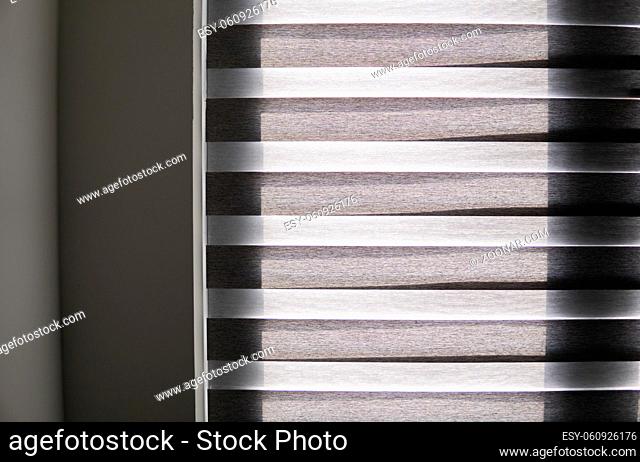 Details of brown fabric roller blinds on the plastic window with wood texture in the living room