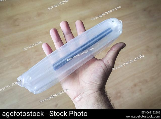 Hand holds a product wrapped with inflatable packaging columns bags. Wooden floor background