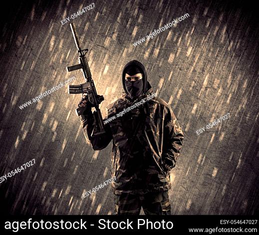Close up of an armed terrorist man with mask on rainy background