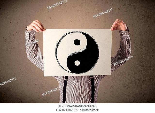 Businessman holding a paper with a yin-yang on it in front of his head