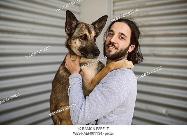 Portrait of young man holding dog