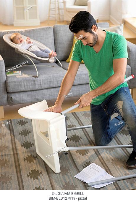 Father setting up highchair in living room