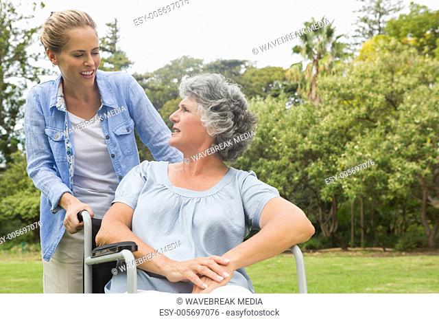 Smiling mature woman in wheelchair talking with daughter