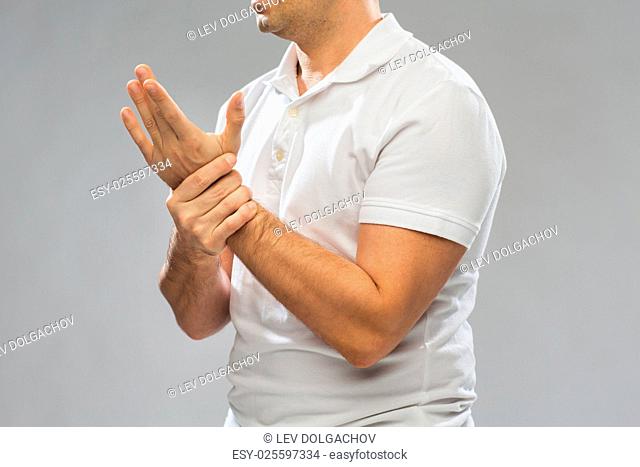 people, healthcare and problem concept - close up of man suffering from pain in hand over gray background