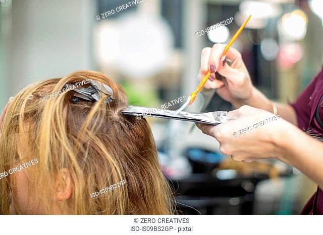 Hairdresser colouring customer's hair in salon