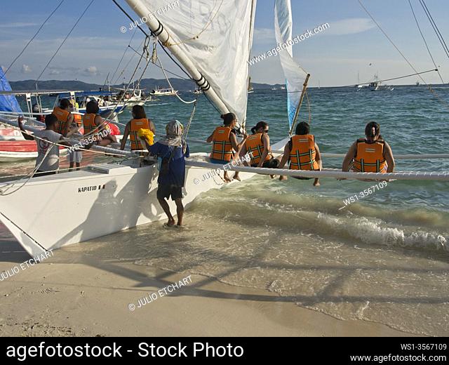 Tourists boarding a traditional panga boat in Boracay, Philippines