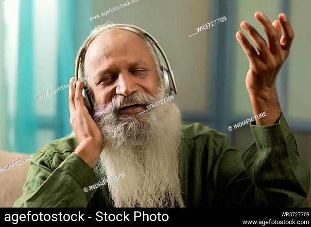 A HAPPY OLD MAN SINGING ALONG WHILE LISTENING TO MUSIC