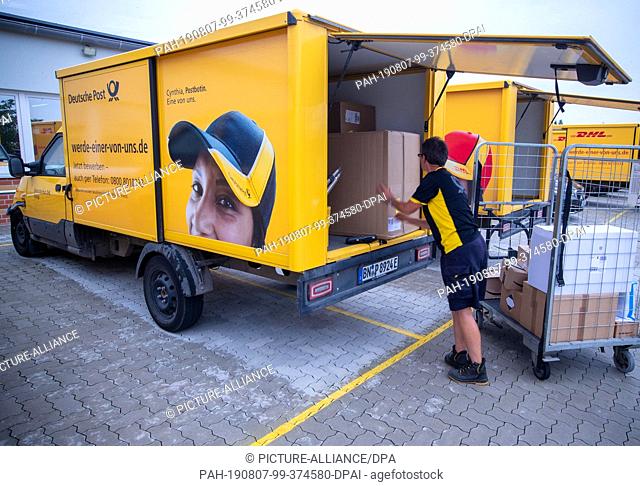 07 August 2019, Mecklenburg-Western Pomerania, Wittenburg: A parcel delivery woman loads a ""street scooter"", an electrically driven transporter