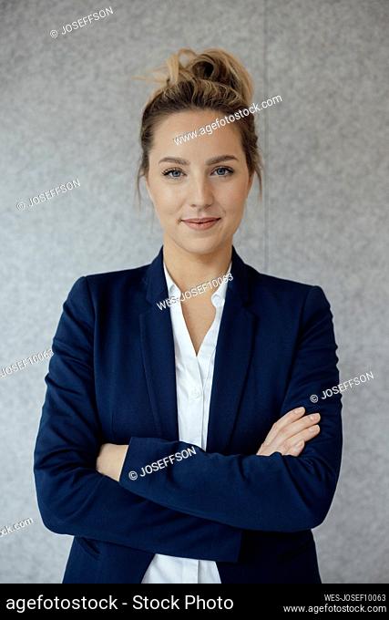 Businesswoman with arms crossed in front of gray wall