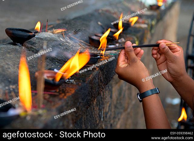Female hands set fire to fragrant sticks in the temple offerings place