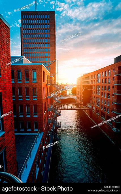 HafenCity. Bridge over canal and red brick buildings in the old warehouse district Speicherstadt in Hamburg in golden hour sunset light, Germany