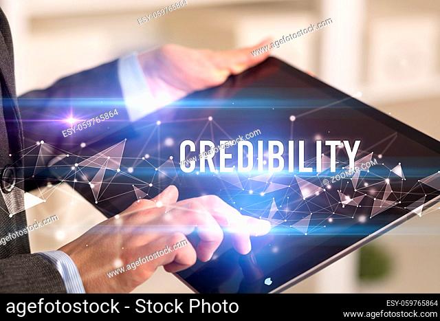 Close up hands using tablet with CREDIBILITY inscription, modern business technology concept