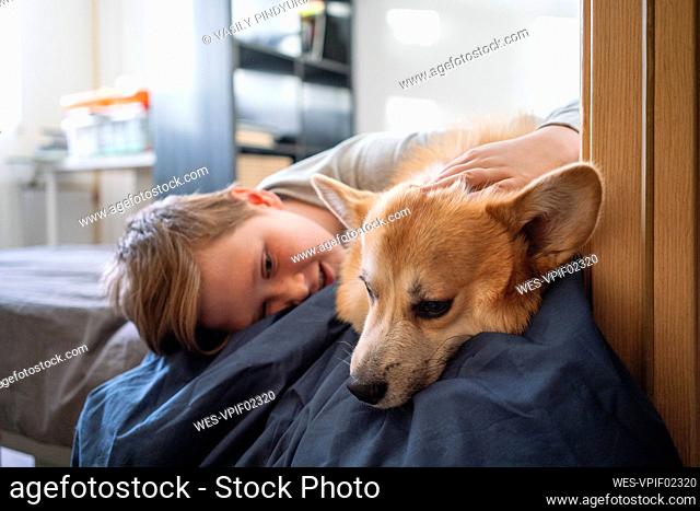 Boy lying on bed stroking his dog